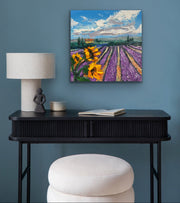 Painting of sunflowers and lavender on a blue wall above a black console table.