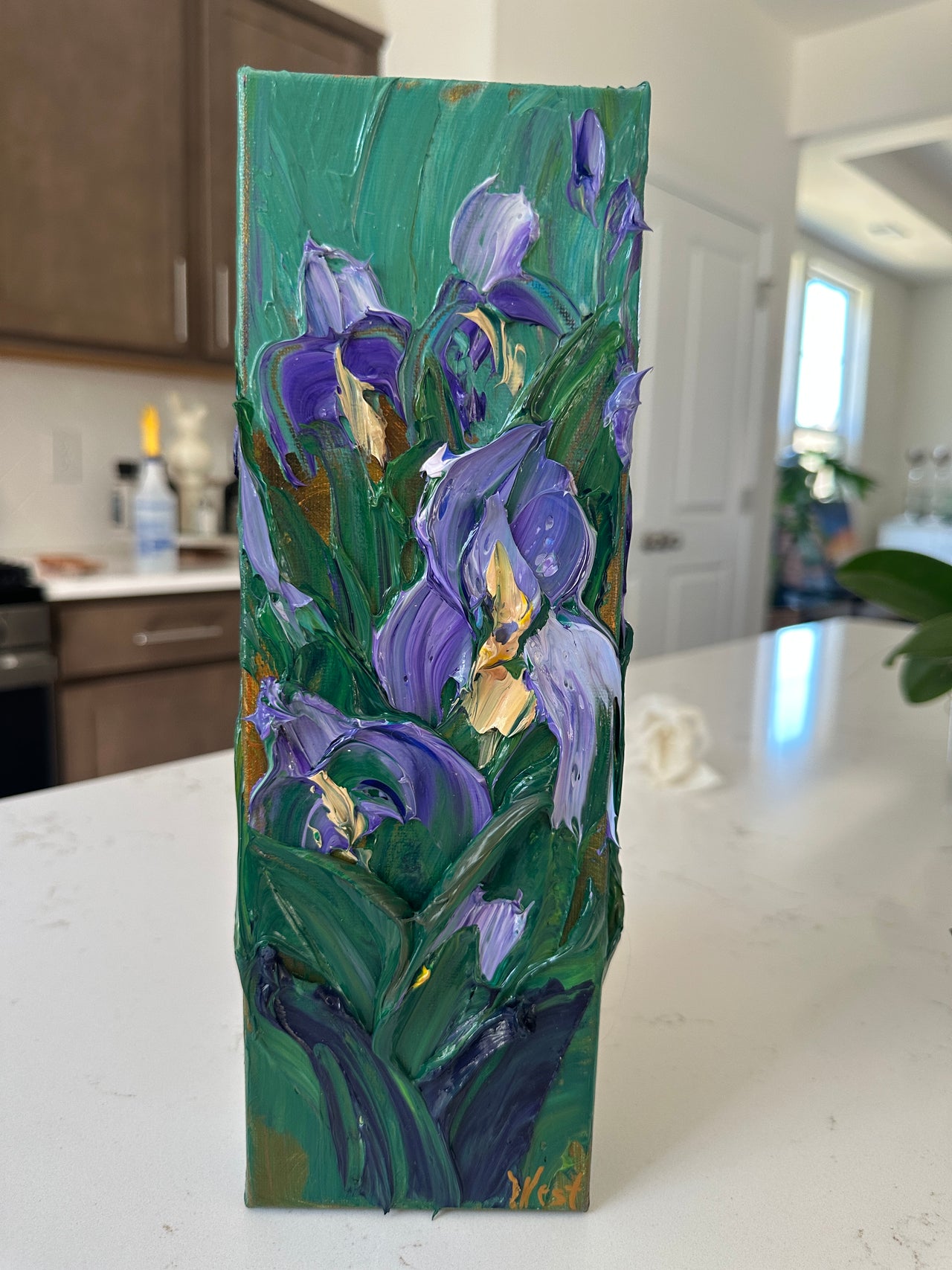 Palette knife impasto painting of purple flowers on a green background, placed on a white surface.