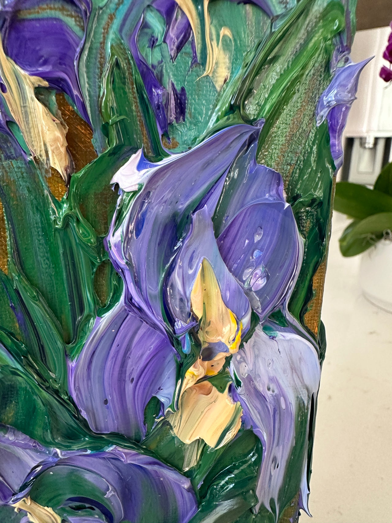 close up of impasto palette knife painted flowers in purple, green, and gold on a textured surface.