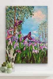 Canvas print of a colorful landscape with flowers and trees on a white wall.