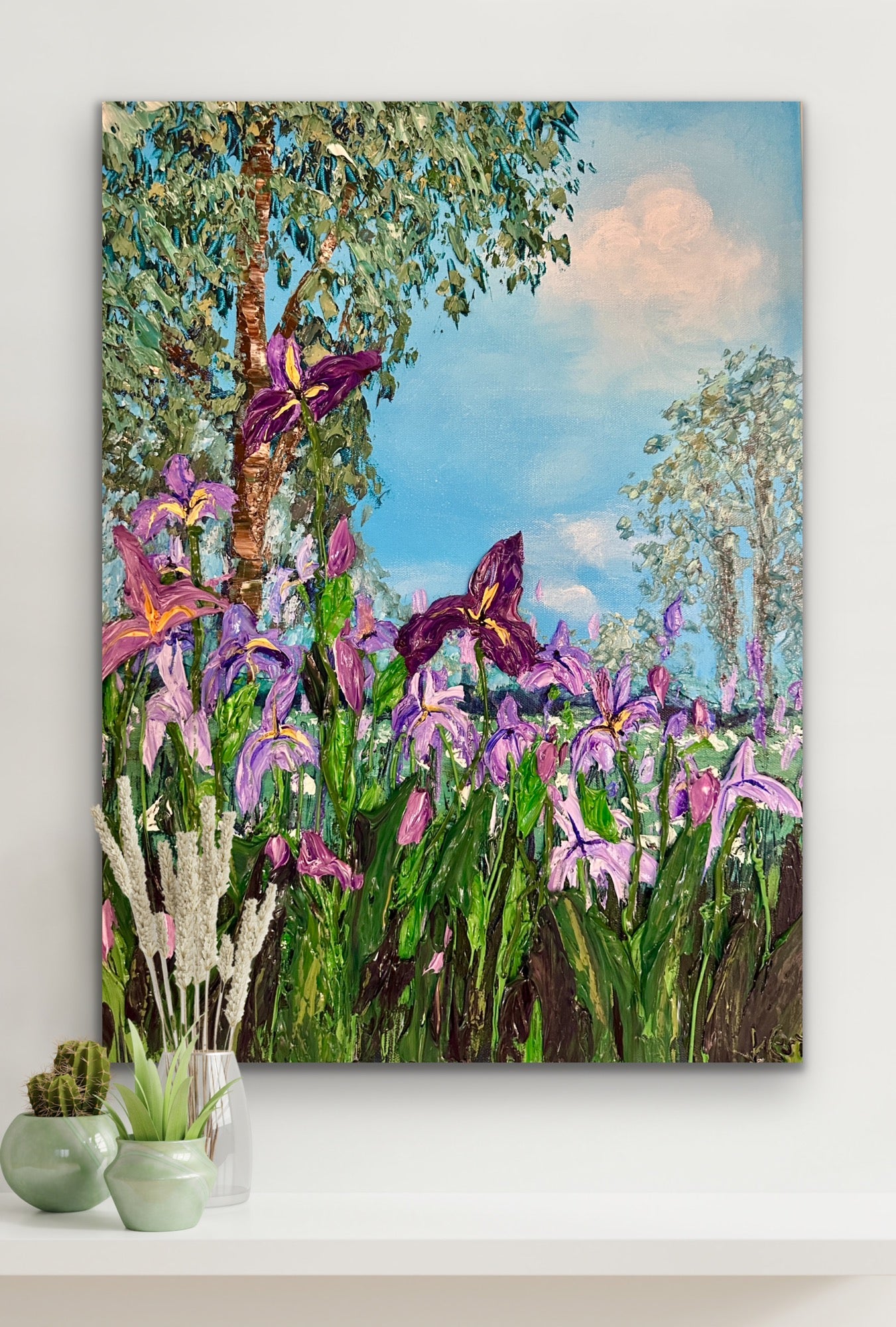 Canvas print of a colorful landscape with flowers and trees on a white wall.