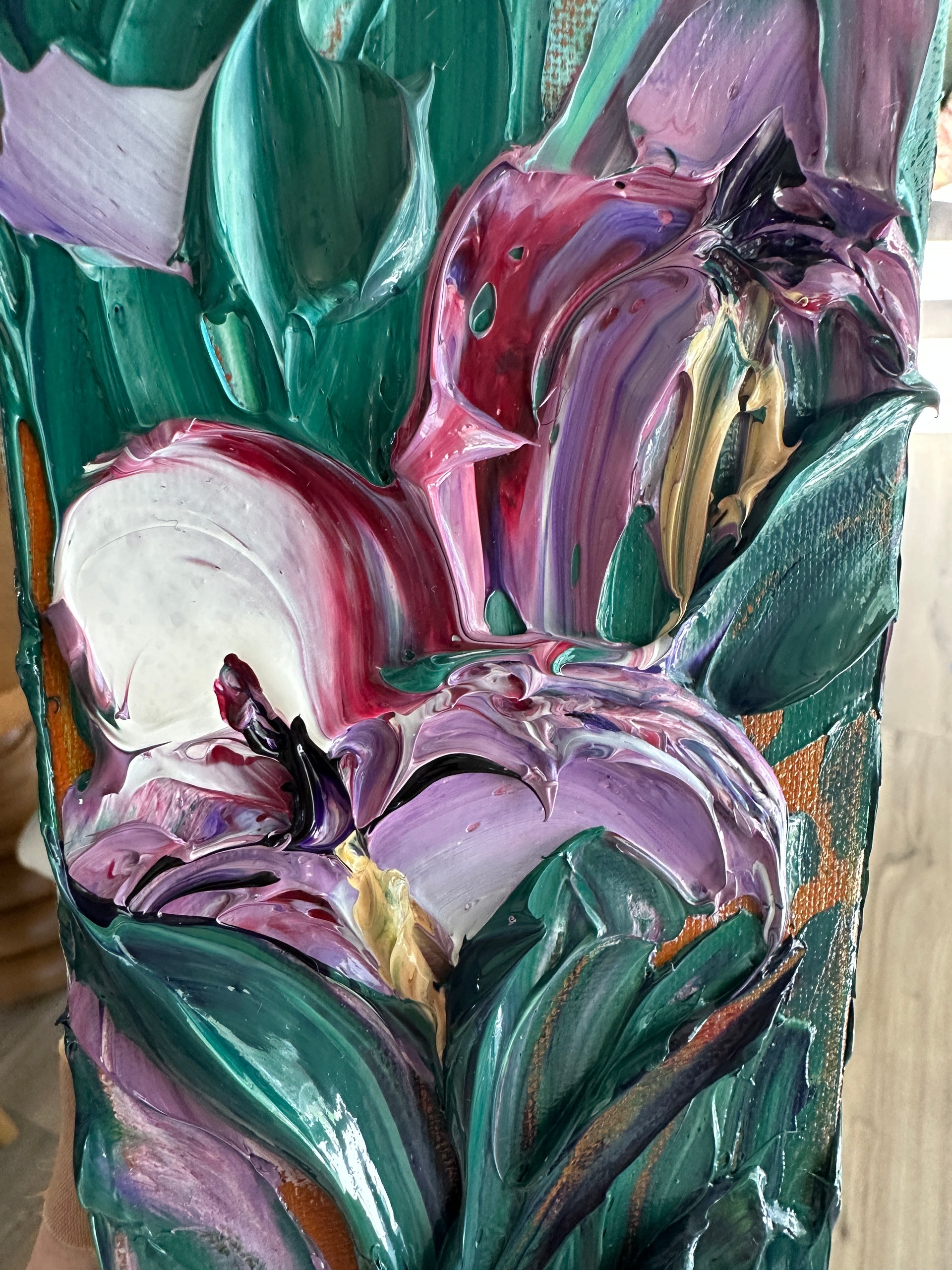 Close up of palette knife art with swirling colors of purple, green, and pink on a textured surface.
