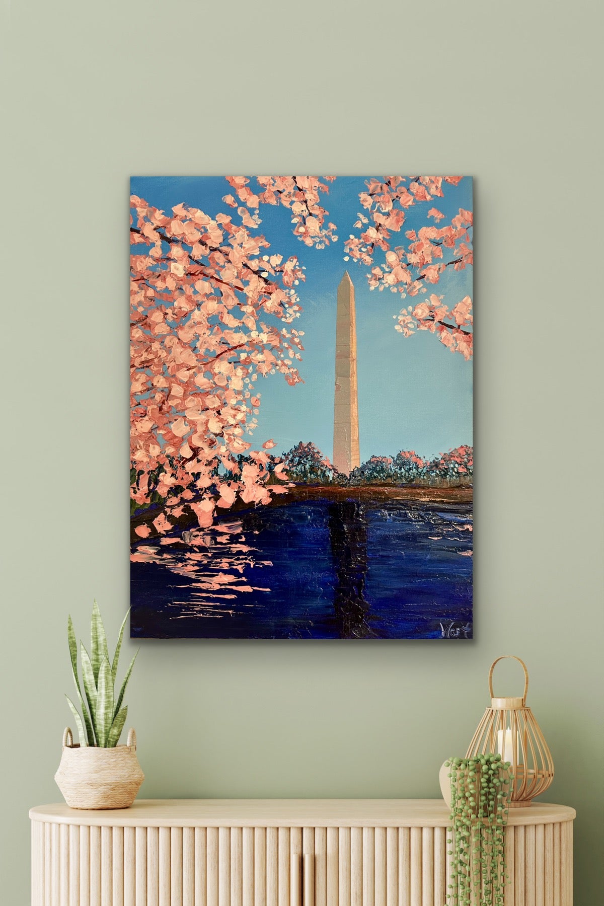 Original painting of cherry blossoms and the Washington Monument on a wall above a console table.