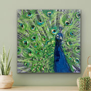 Painting of a peacock with vibrant green feathers and a blue body on a light green wall.