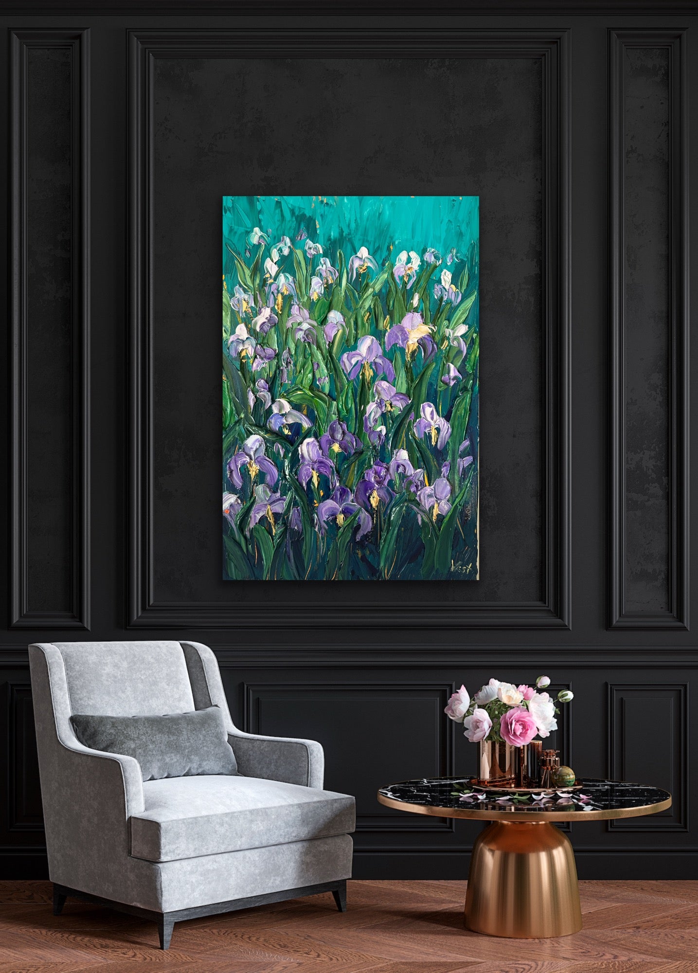 Palette knife impasto painting of purple iris flowers on a dark wall with a gray armchair and small table in the foreground.