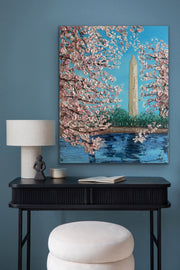 Artistic depiction of cherry blossoms and a monument on a blue wall above a black console table.
