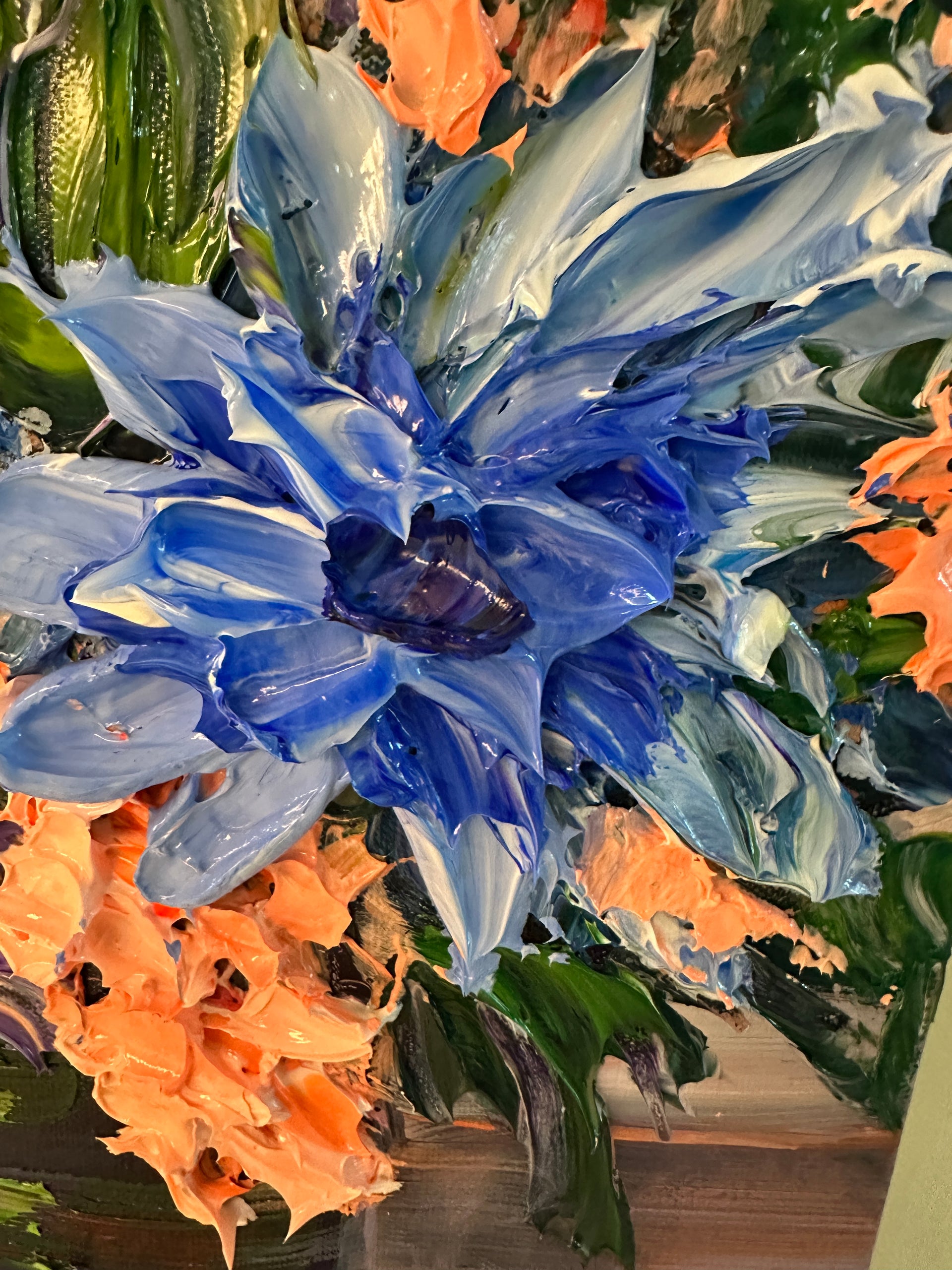 Close-up of a blue palette knife painting of blue flower with green and orange accents