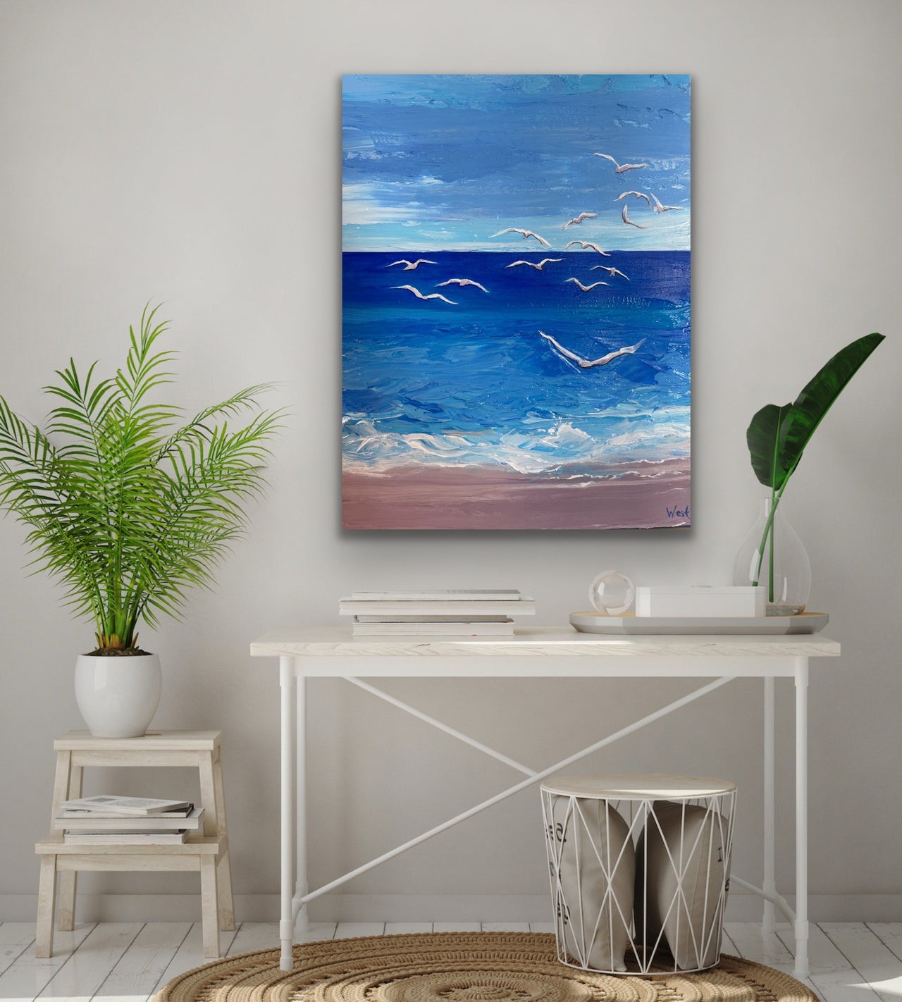 Palette knife impasto painting of a beach scene with seagulls above a desk and plants.